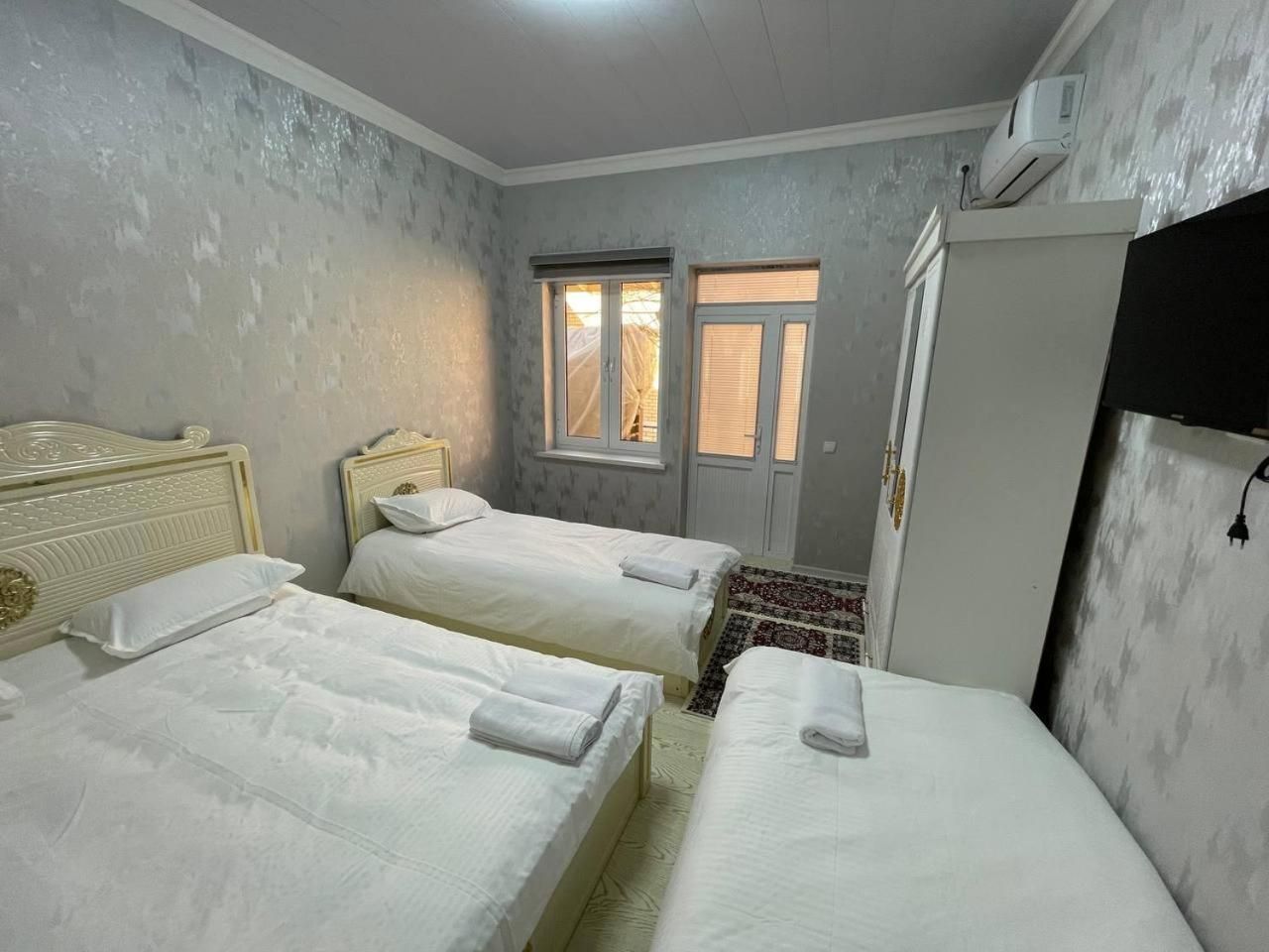 A room with two beds, a window, a door, and an air conditioning unit.