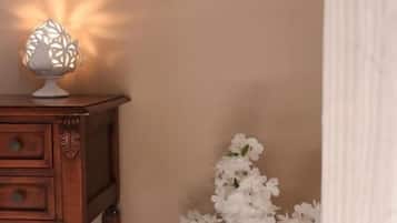 A wooden nightstand with a decorative lamp and a vase of white flowers.