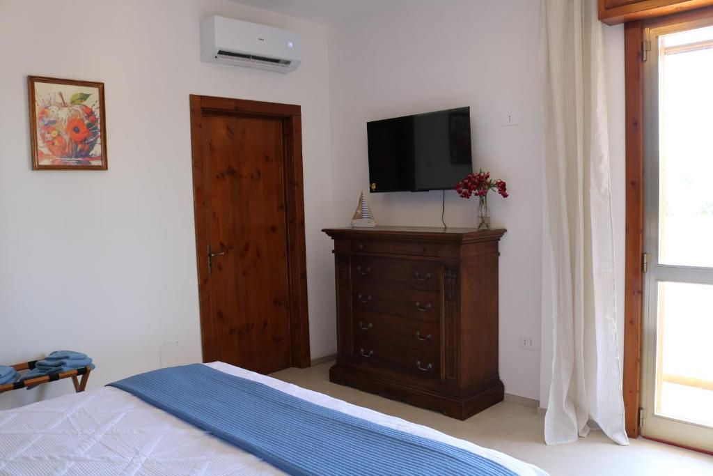 Un dormitorio con una cama, un armario de madera, un televisor de pantalla plana y un ventanal con cortinas.