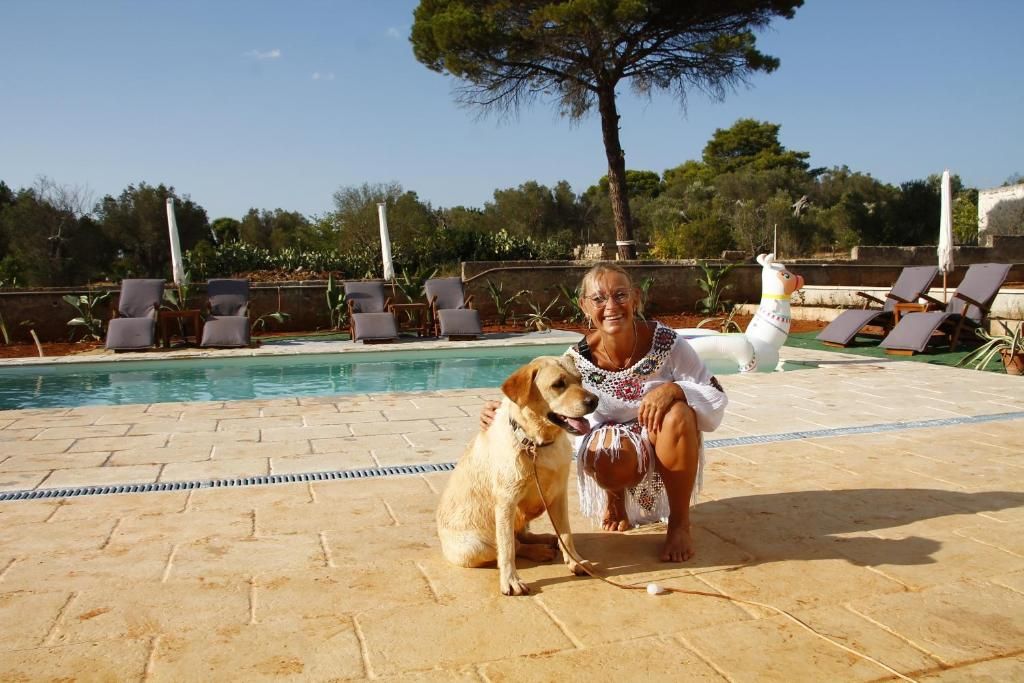 A pool area with lounge chairs and a dog.