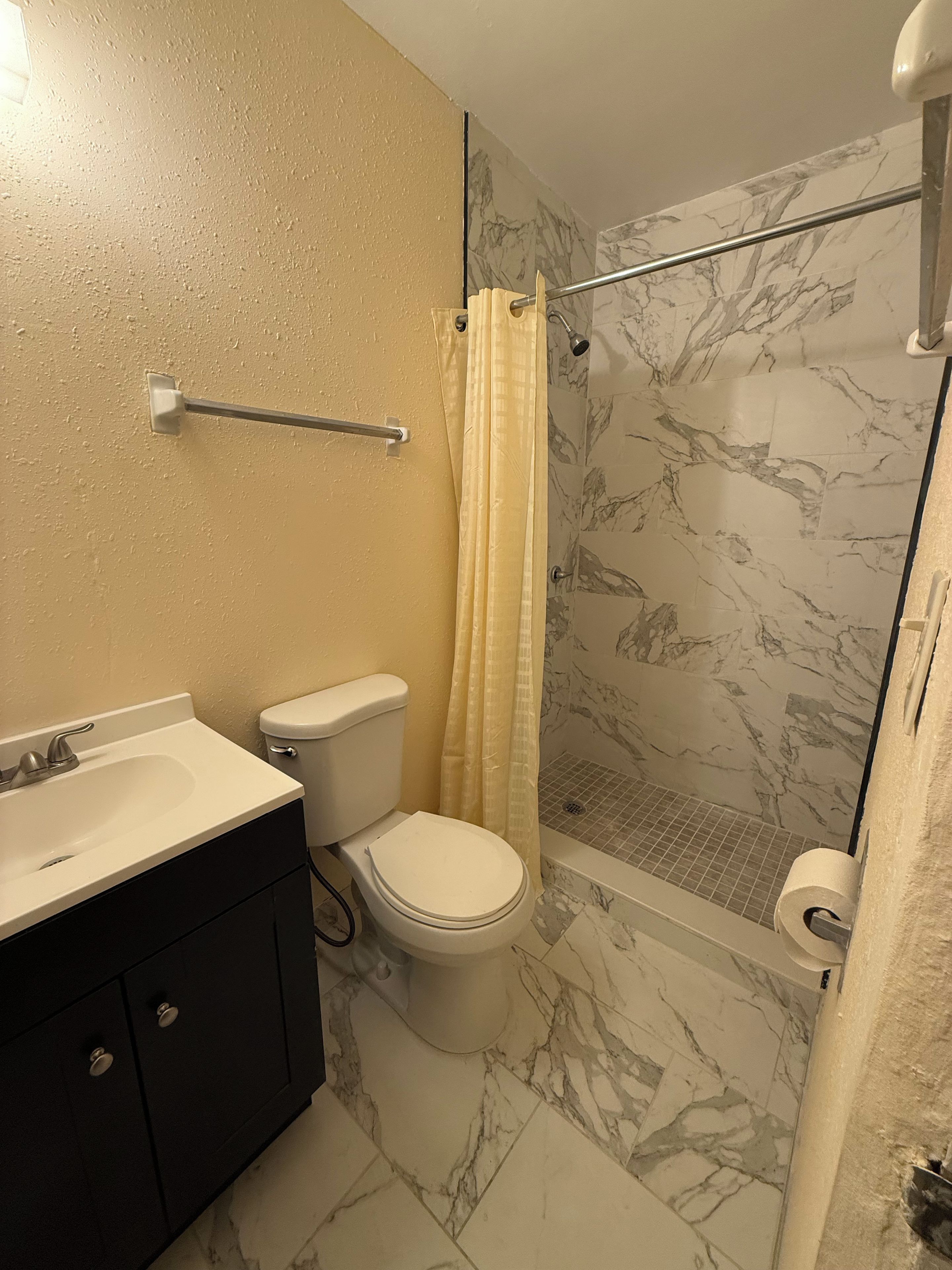 A bathroom with a toilet, sink, and shower area.