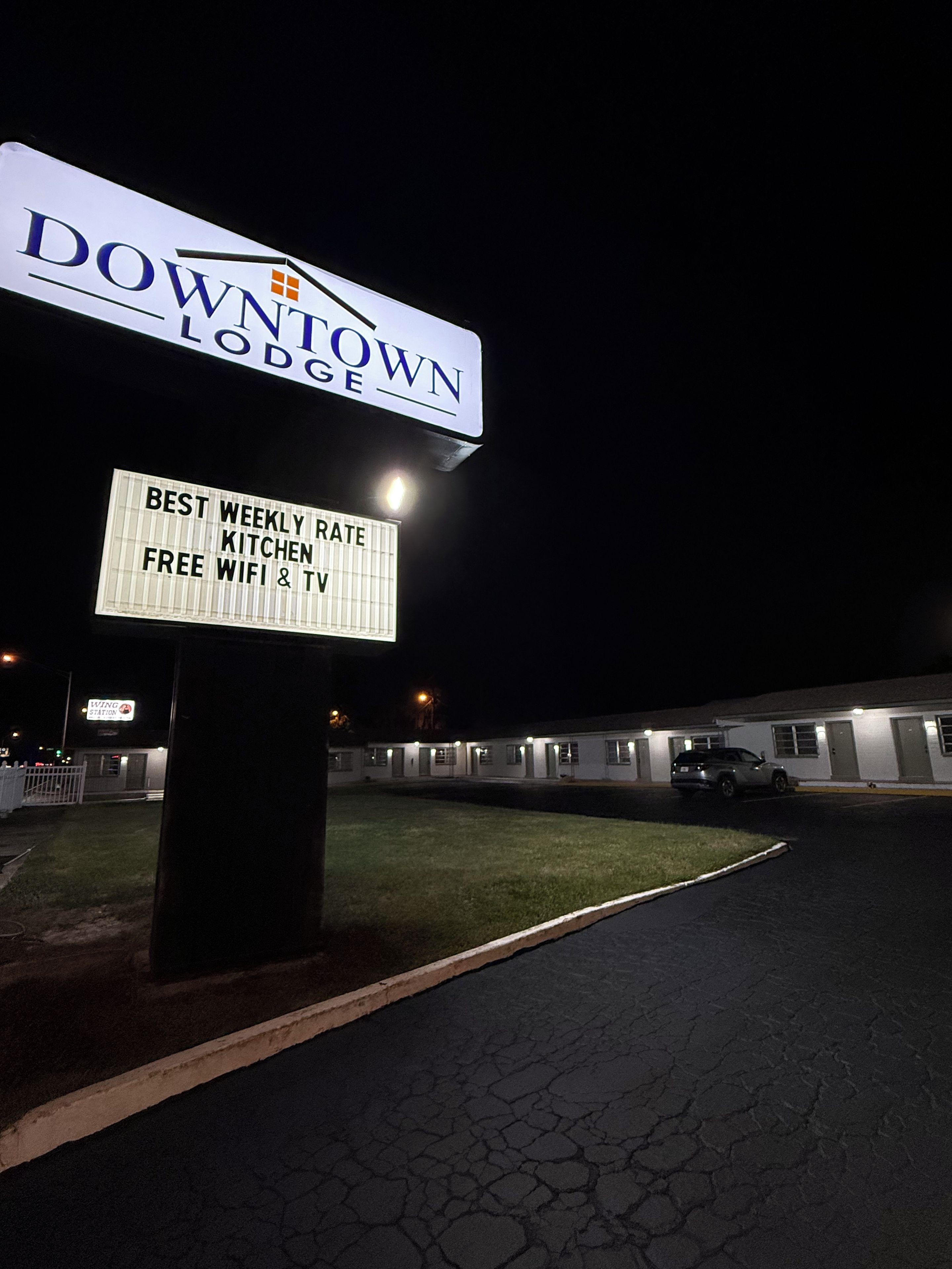A sign for Downtown Lodge with amenities including best weekly rate, kitchen rate, free wifi, and TV.