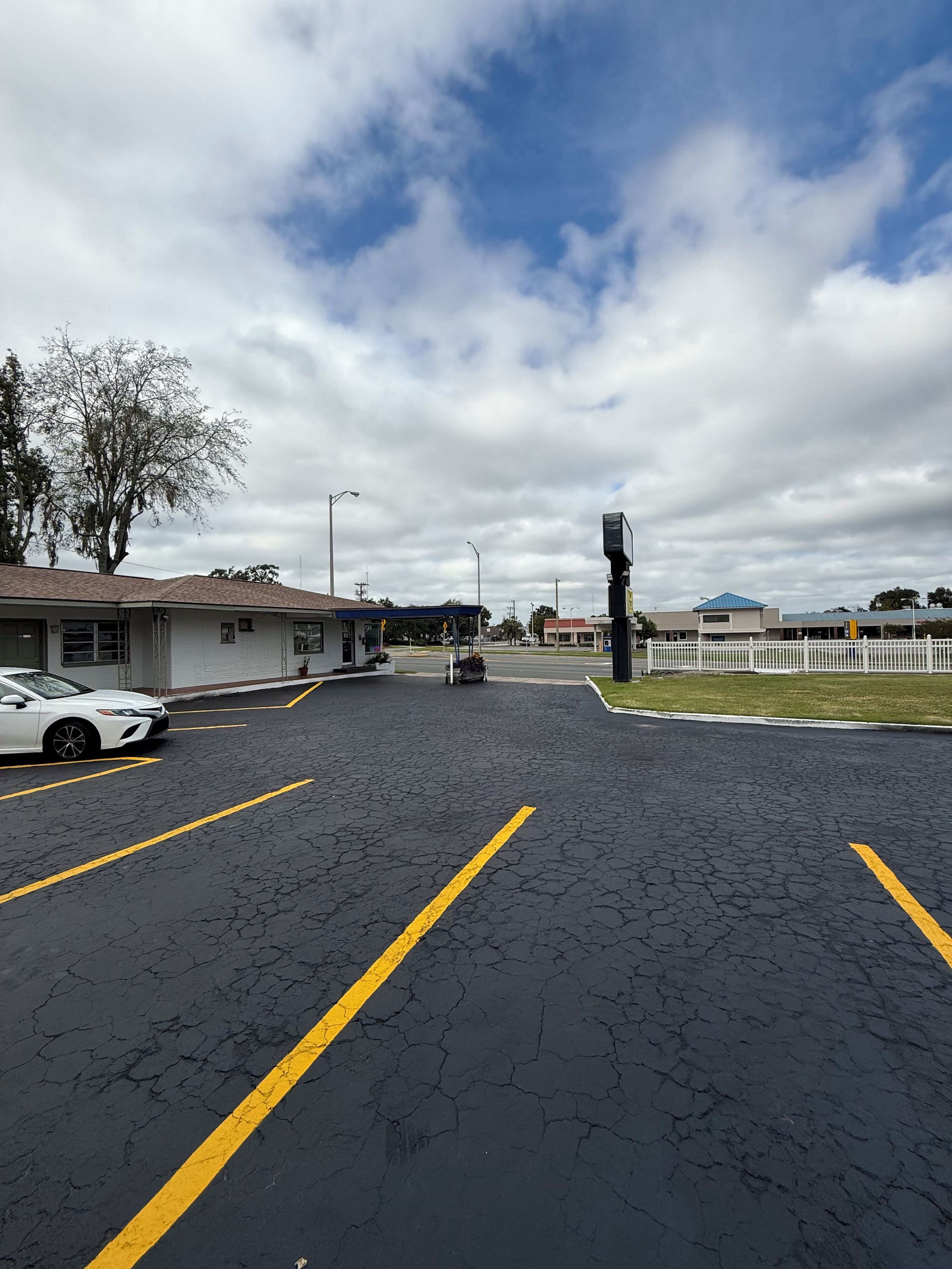 A parking lot with marked lanes and a white fence in the background.