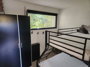 Une chambre avec un lit superposé, une armoire et une fenêtre donnant sur un paysage verdoyant.