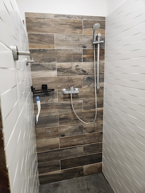 Un espace douche avec un mur en bois, une pomme de douche à main et un flexible de douche.