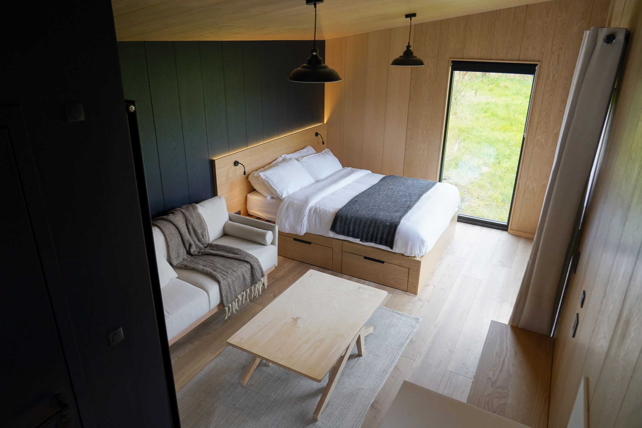 Un dormitorio moderno con cama, sofá, mesa y vistas al exterior.