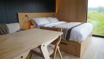 A bedroom with a bed, a wooden desk, and a view of the outdoors.