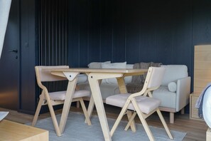 Ein modernes Zimmer mit einem Holztisch und -stühlen, einem grauen Sofa und einer dunkelblauen Wand.