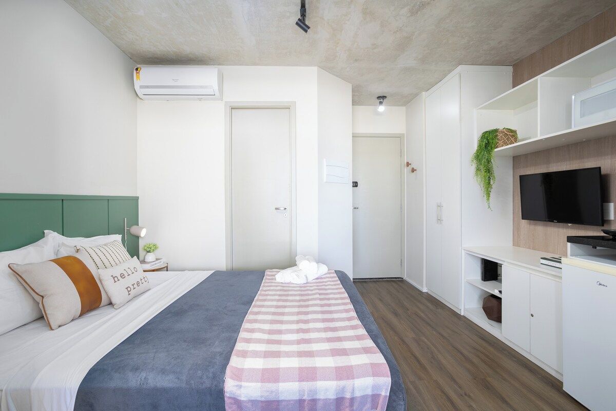 A hotel room with a bed, a television, a desk, and a wardrobe.