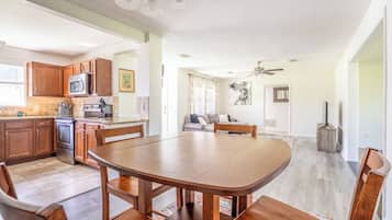 Cozinha ampla com armários de madeira, mesa de jantar e ventilador de teto.