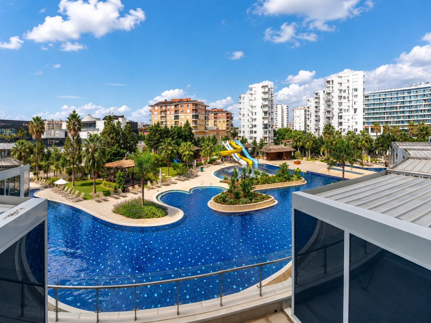 Un resort con una grande piscina, palme e moderni edifici sullo sfondo.