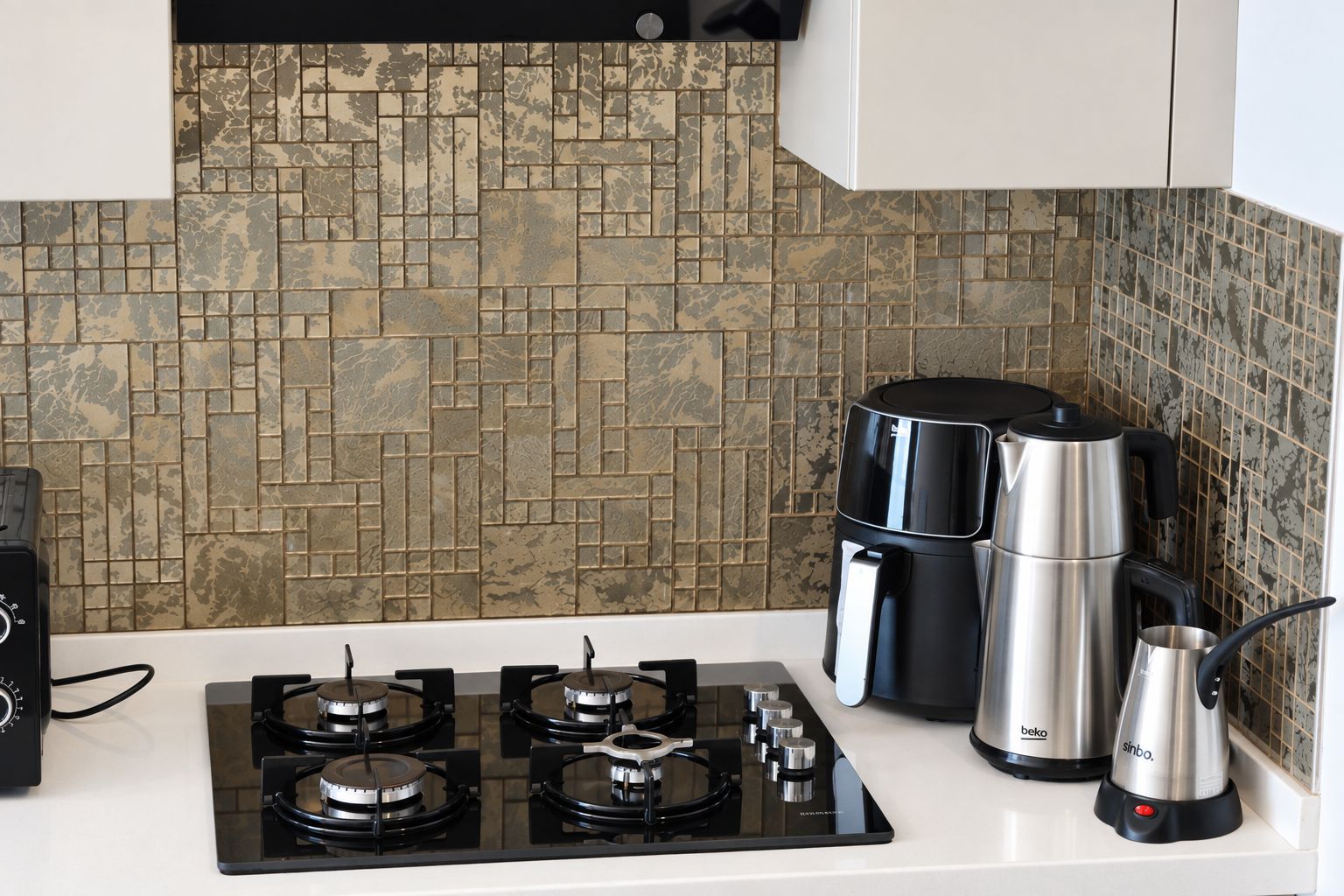 Una cucina con fornello a gas, una macchina da caffè e un bollitore.