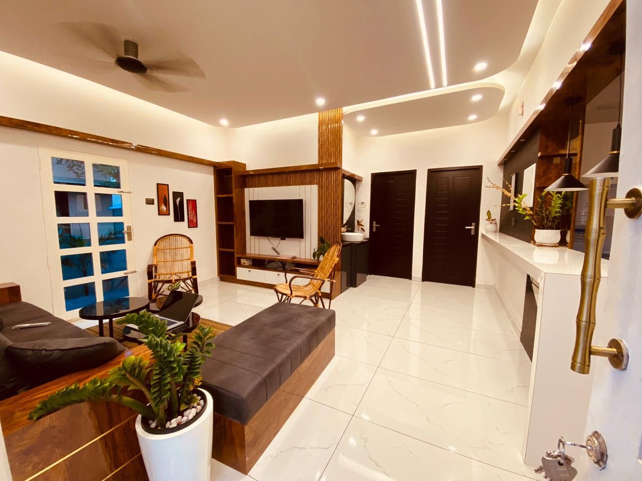 A modern living room with a sofa, a coffee table, and a TV. There is a door leading to another room.