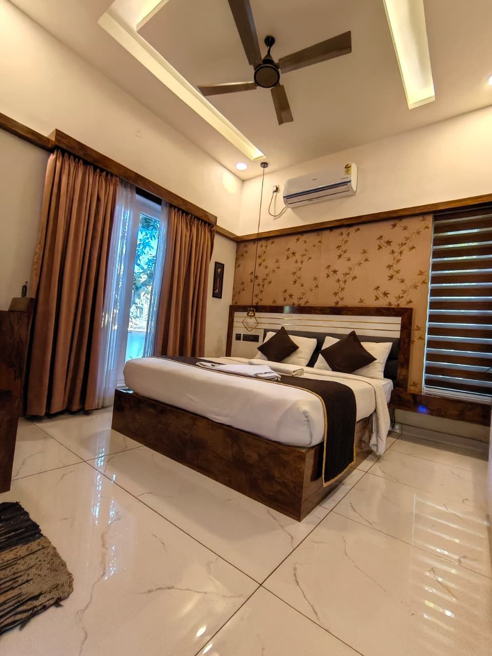 Un dormitorio con cama, ventilador de techo, aire acondicionado y vistas al exterior a través de una ventana.