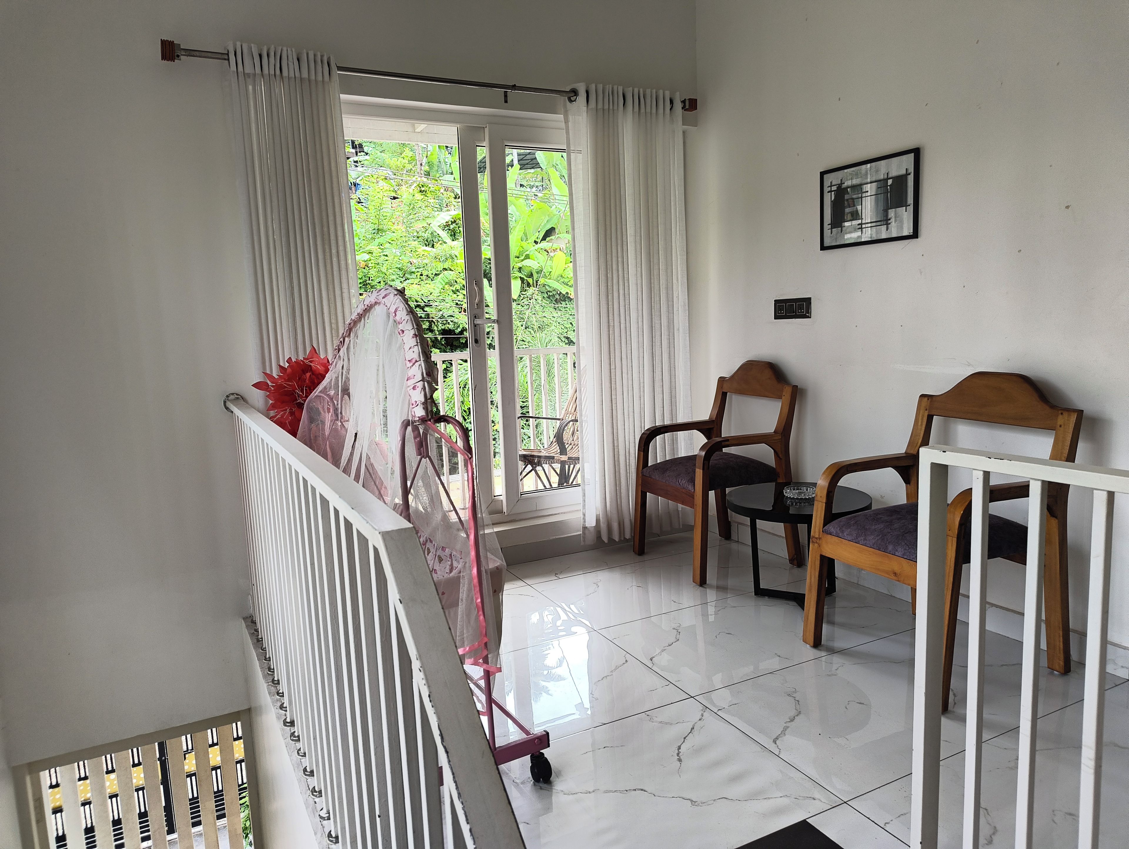 Una habitación con balcón, una silla, una mesa y un radiador.