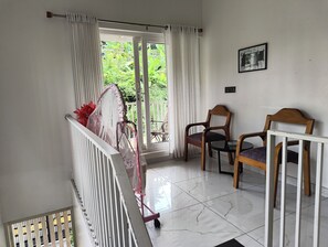 Una habitación con balcón, una silla, una mesa y un radiador.