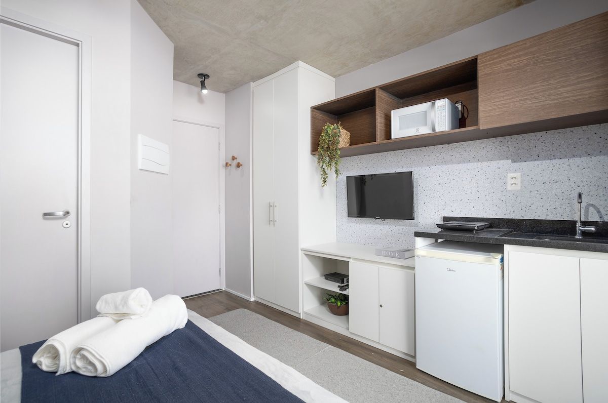 Une chambre d’hôtel compacte équipée d’une kitchenette, d’un téléviseur à écran plat, d’un four à micro-ondes et d’un petit réfrigérateur.
