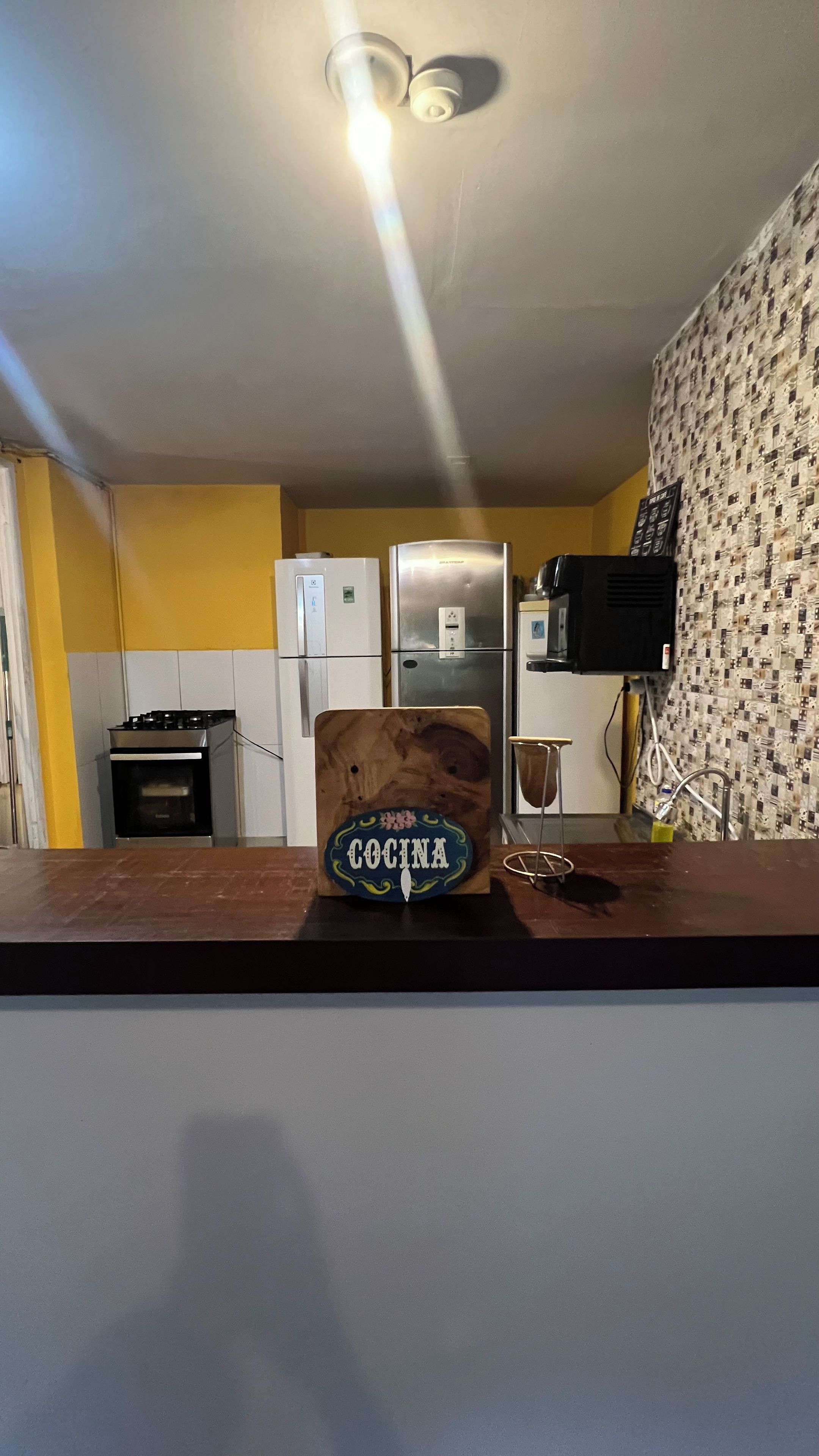 Una cocina con un letrero de madera que dice 'Cocina', un refrigerador de acero inoxidable, un microondas y una estufa.