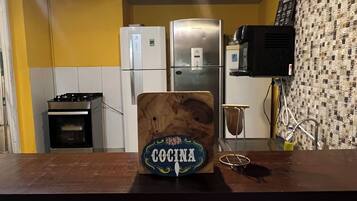 A kitchen with a wooden sign labeled 'Cocina,' a stainless steel refrigerator, a microwave, and a stove.