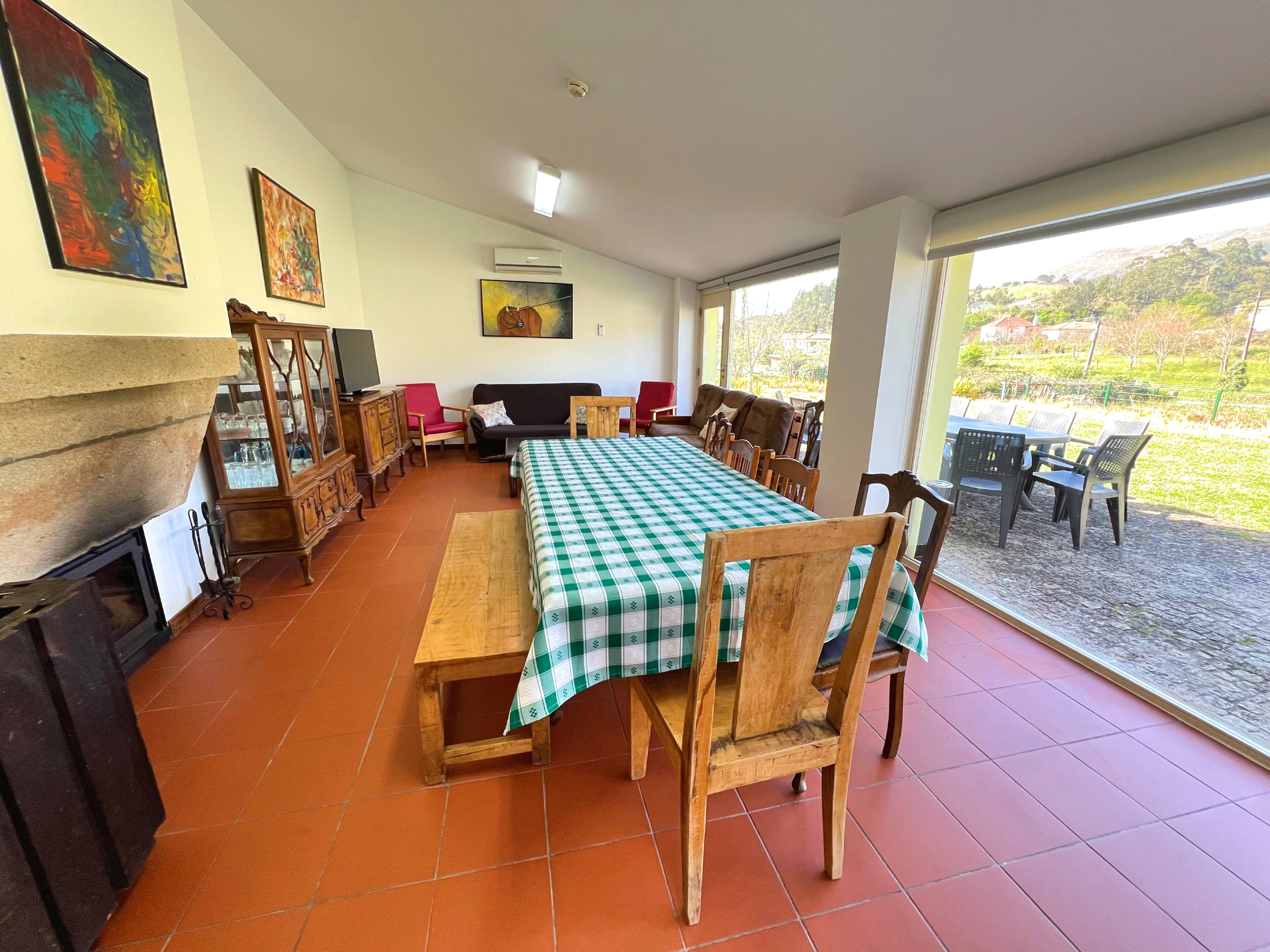 A dining area with a checkered tablecloth, wooden chairs, a sofa, and a television.