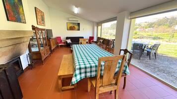 A dining area with a checkered tablecloth, wooden chairs, a sofa, and a television.