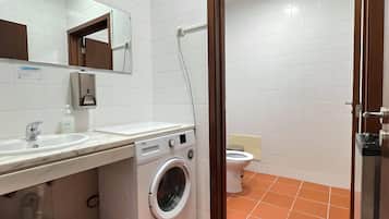 A modern bathroom with a washing machine, sink, and toilet.