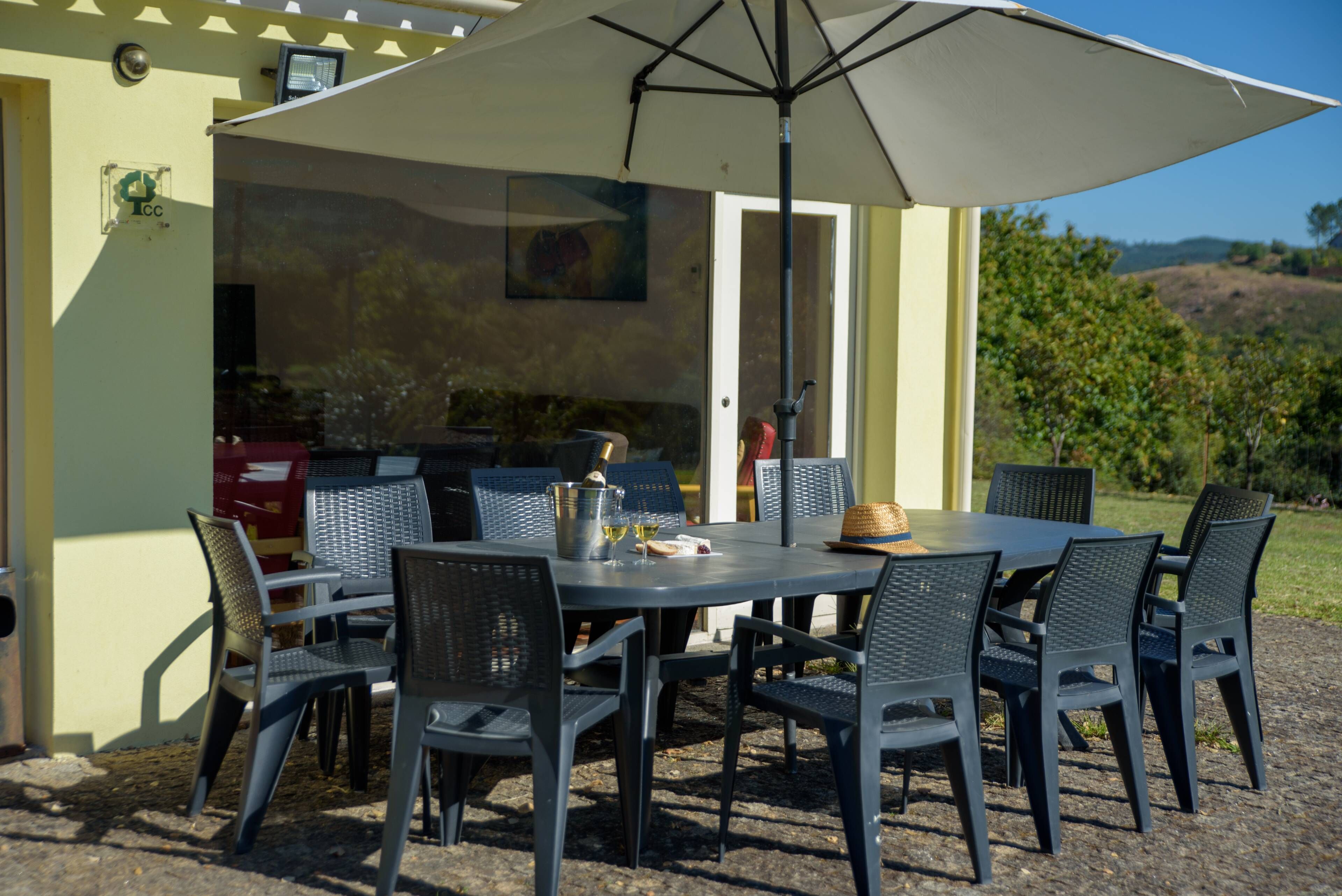 Un área de comedor al aire libre con mesa y sillas, una parrilla y vistas del paisaje circundante.