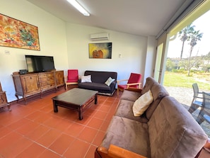 Ein Wohnzimmer mit einer Couch, Sesseln, einem Couchtisch, einem Fernseher und Kunstwerken an den Wänden.