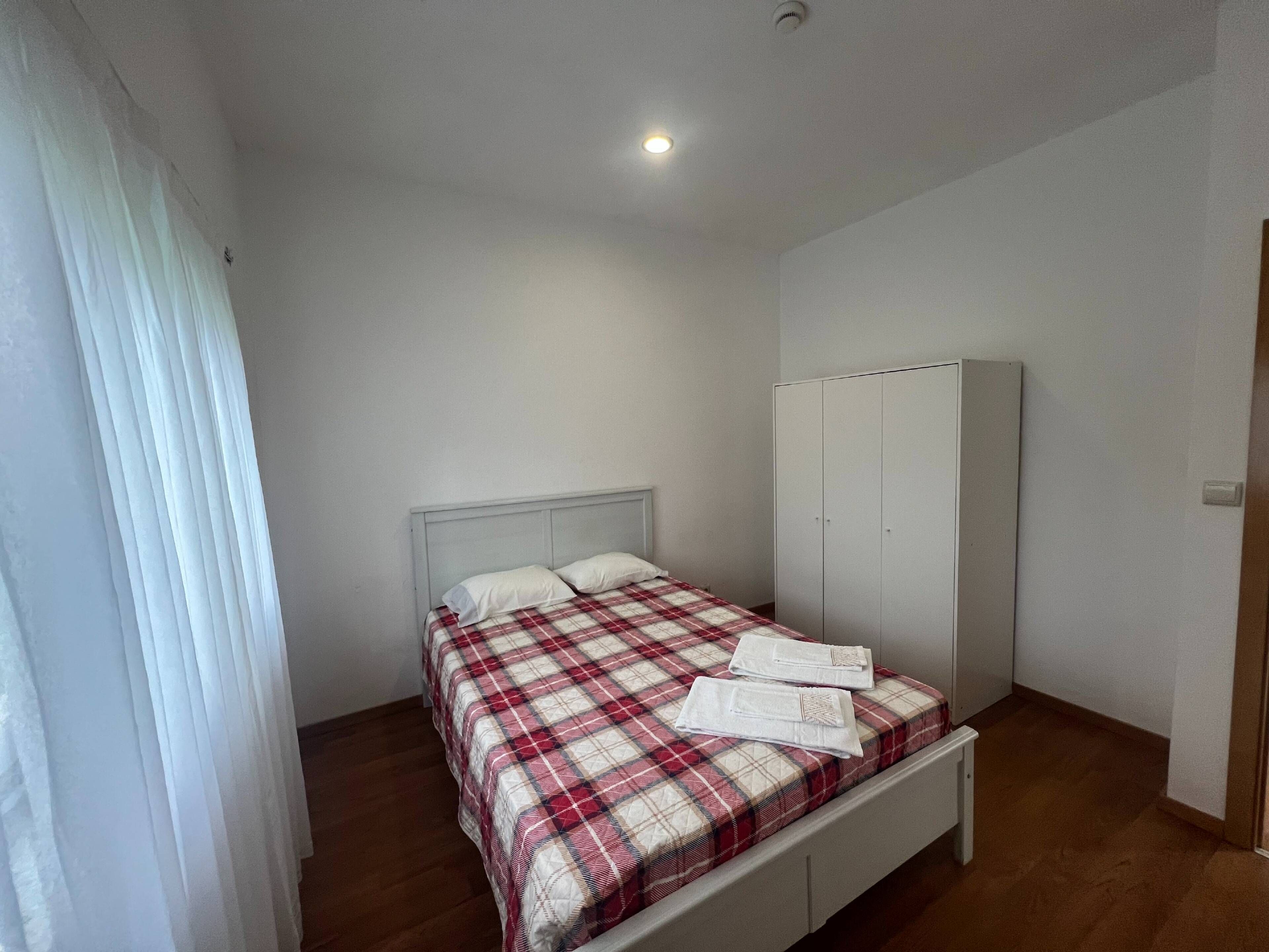 Une chambre à coucher avec un lit, une armoire et une fenêtre avec des rideaux.