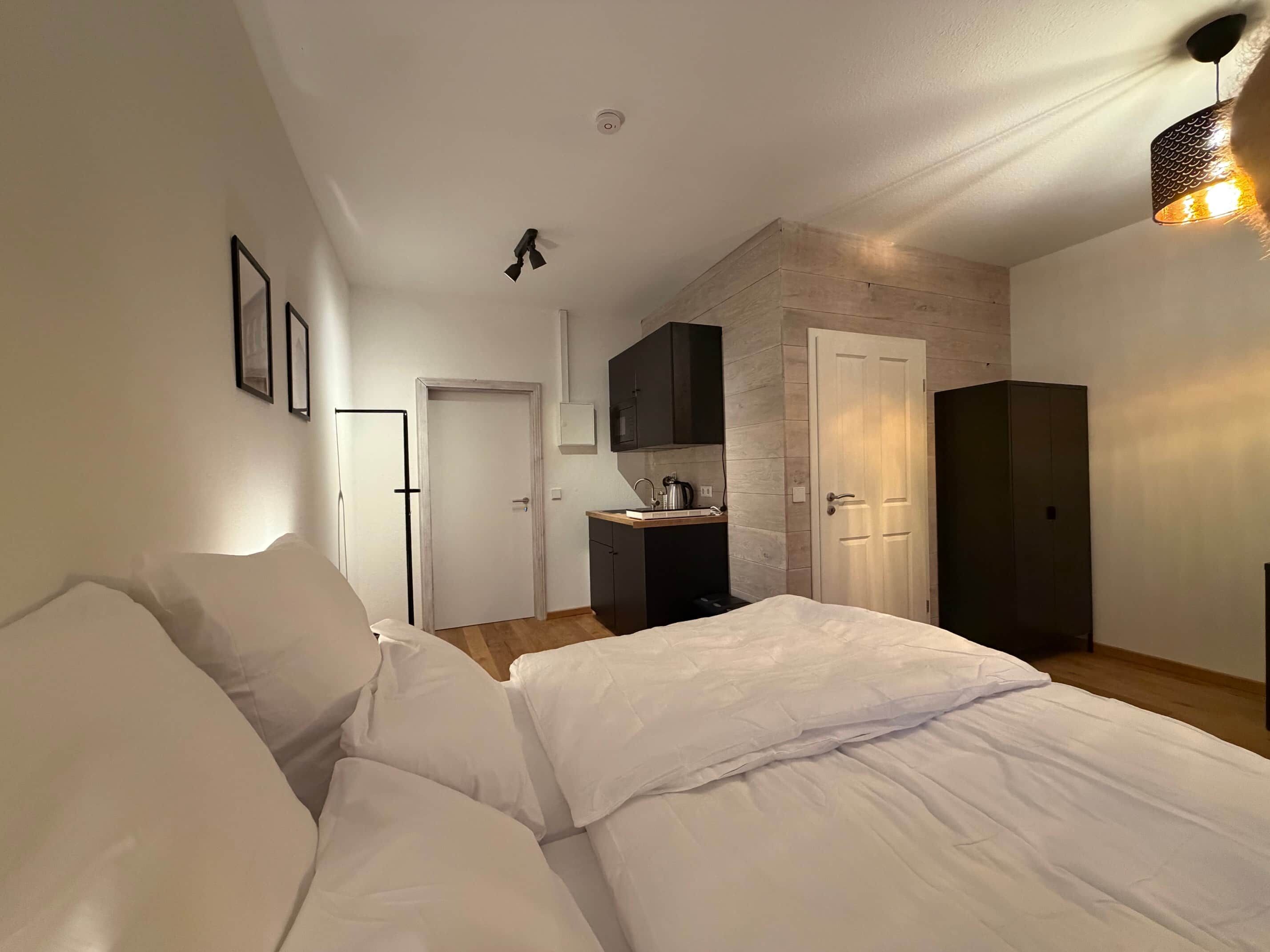 Ein Schlafzimmer mit Bett, einer Küchenzeile und einer Tür zu einem anderen Raum.