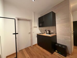 Eine kleine Küche mit Mikrowelle, Spüle und schwarzen Schränken.