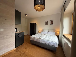 A modern bedroom with a bed, bedside tables, a wardrobe, and a hanging light fixture. - Double room in historic factory (Haldensleben)