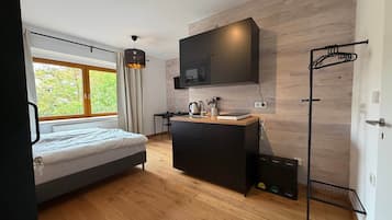 Une chambre moderne avec un lit, une petite kitchenette et une fenêtre avec des rideaux.