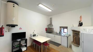 A modern kitchen with white cabinets, a microwave, a gas stove, and a dishwasher. There is a small dining area with a table and chairs.