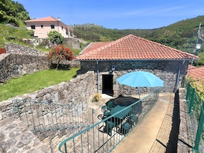A stone building with a red-tiled roof, a covered outdoor seating area with a blue umbrella, and a staircase leading to a higher level. - Rural Retreat Ponte de Lima (Ponte de Lima)