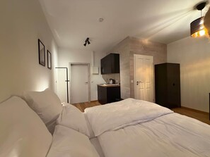 Ein Schlafzimmer mit Bett, einer Küchenzeile und einer Tür zu einem anderen Raum.