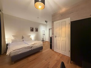 Ein Schlafzimmer mit Bett, Nachttischen, einer Stehlampe und einem Kleiderschrank.