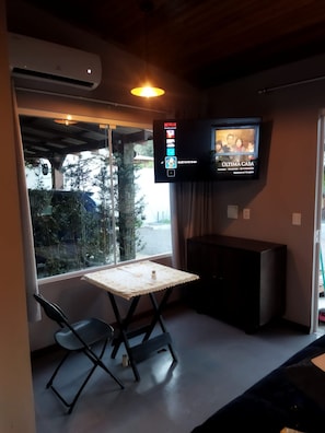 A room with a TV displaying a movie, a table with chairs, and an air conditioning unit. - New Listing (Vera Cruz)
