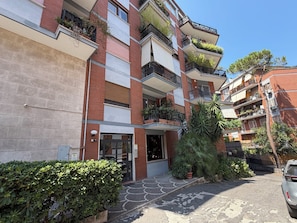 A multi-story residential building with balconies, a gated entrance, and surrounding greenery. - New Listing (Roma)