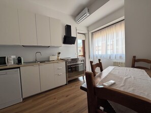 A compact kitchen with white cabinets, a microwave, a toaster, and a stove. - New Listing (Roma)