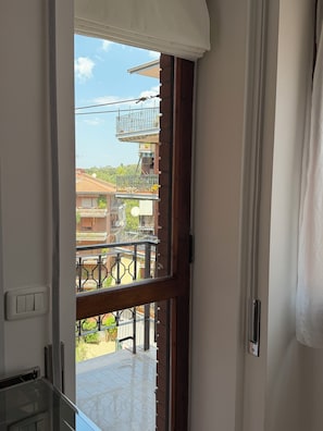 Blick vom Balkon mit Metallgeländer, blauem Himmel und Gebäuden im Hintergrund.