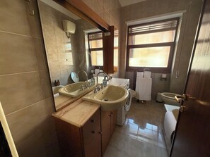 Et badeværelse med to håndvaske, toilet og spejl.