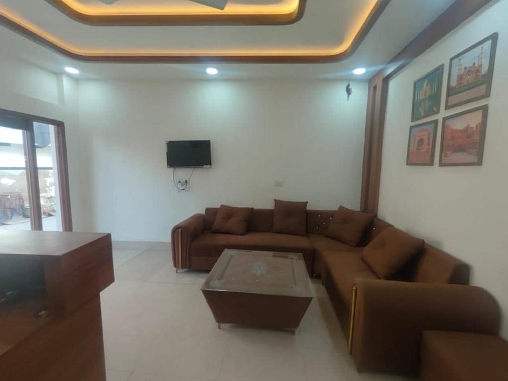 A living room with a sectional sofa, a coffee table, and a flat-screen TV mounted on the wall.