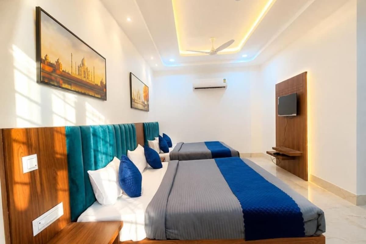 Een hotelkamer met een bed, nachtkastjes, een televisie en kunstwerken aan de muur.