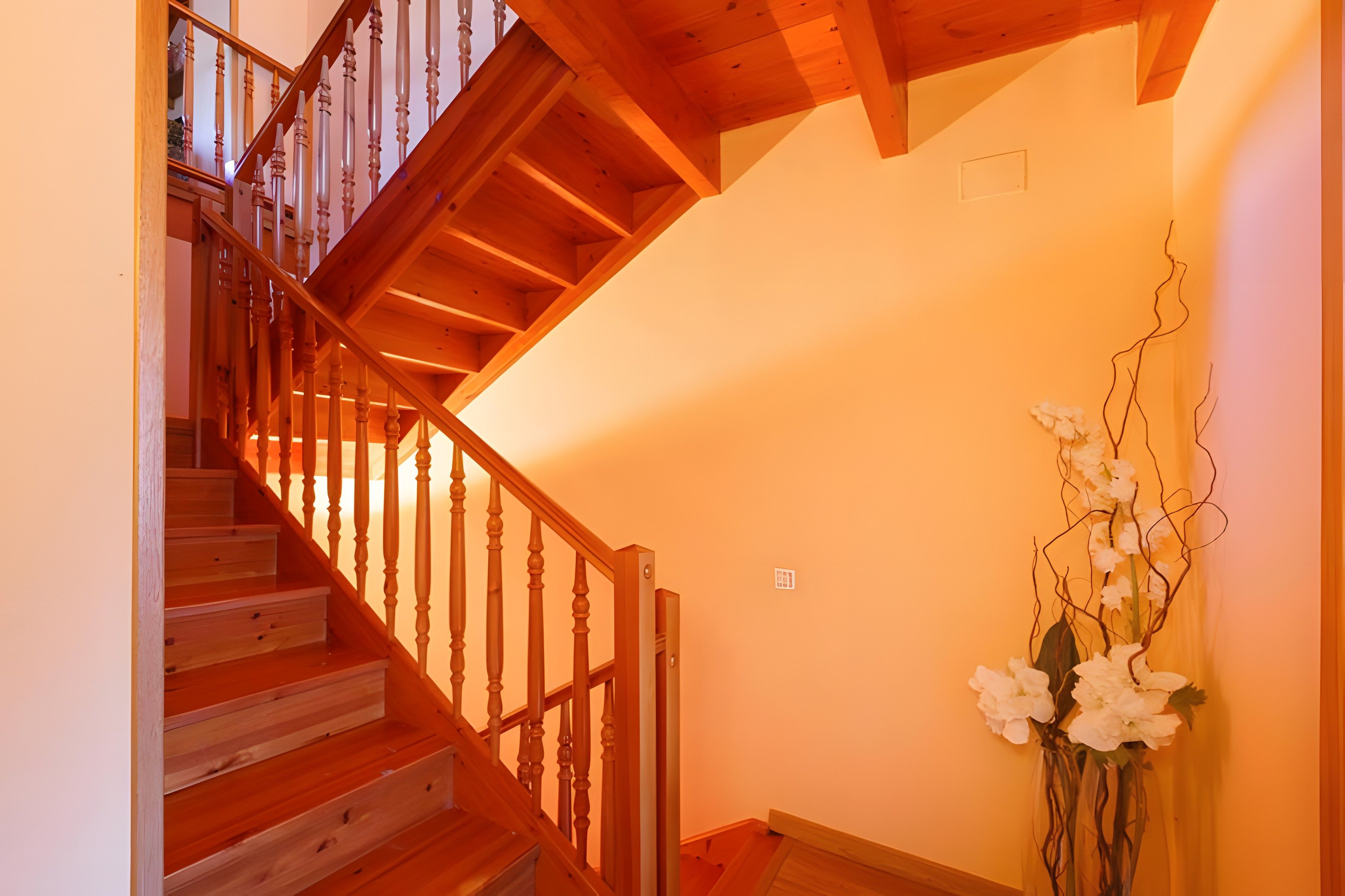A wooden staircase with a railing, leading to an upper floor.