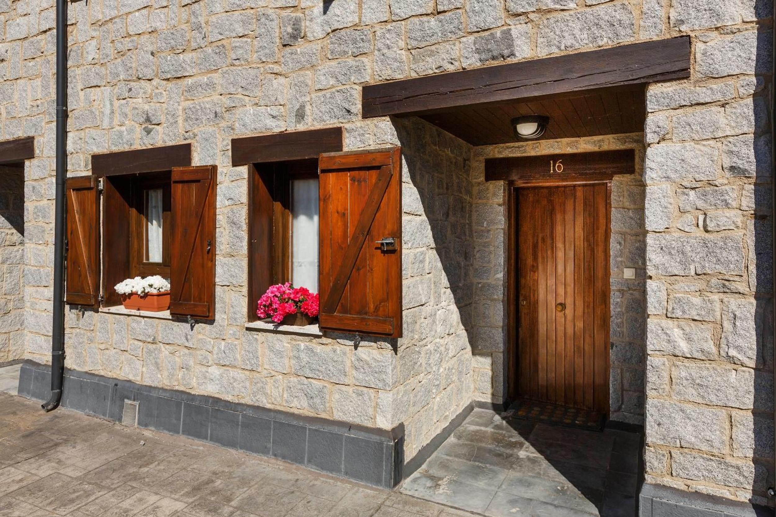 A stone building with two wooden doors and windows with shutters.
