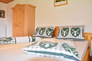 Ein Schlafzimmer mit einem Bett, zwei Kissen, einem Holzschrank und einem gerahmten Bild an der Wand.