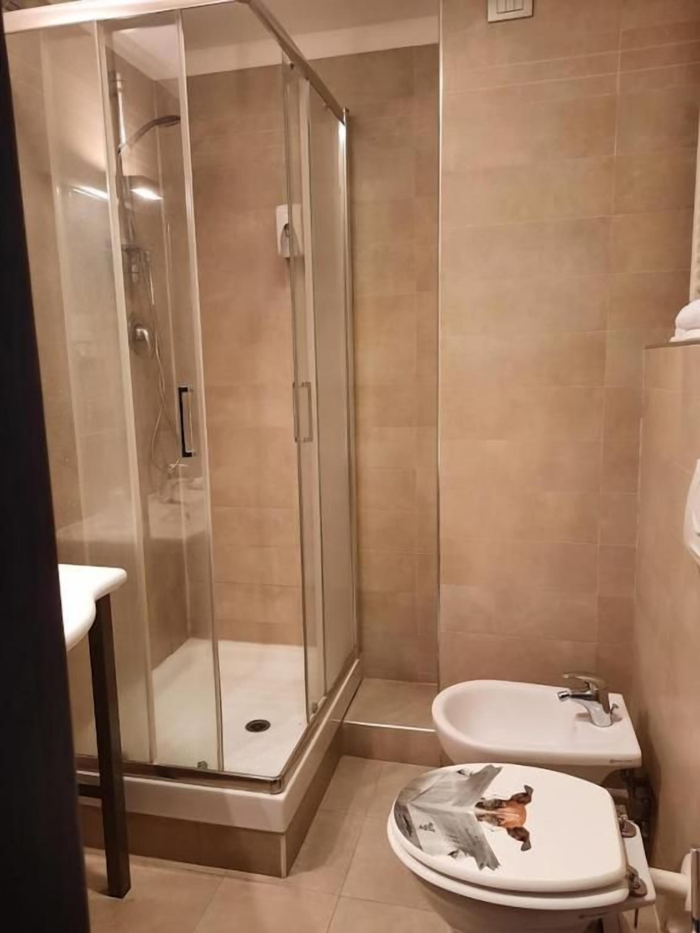 Un baño con ducha envuelta en vidrio, un lavabo blanco y un inodoro.