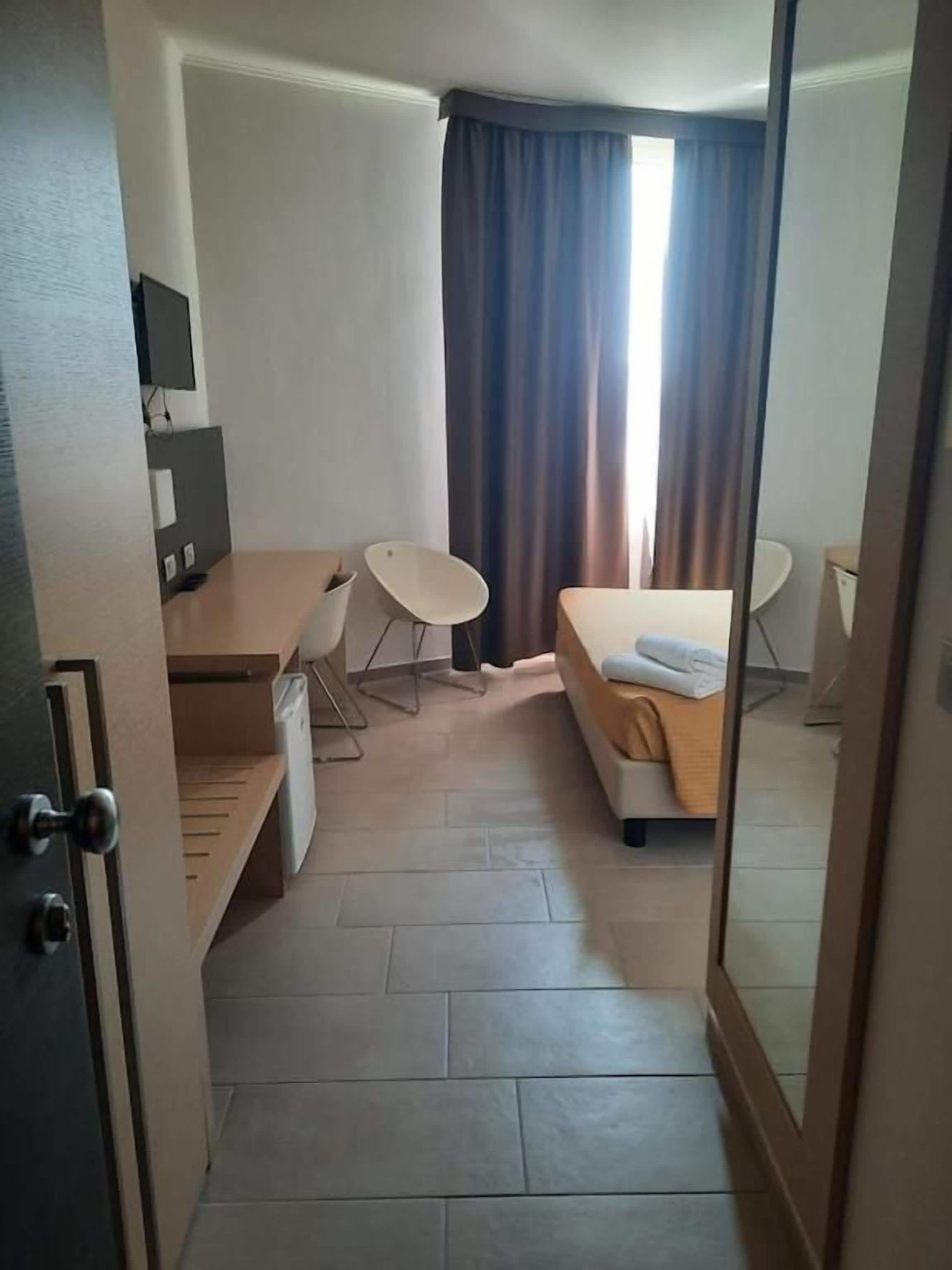 Una habitación de hotel con cama, escritorio, silla y televisión.