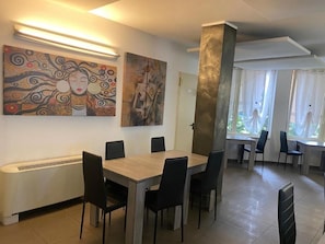 Un comedor con mesa y sillas, una obra de arte en la pared y un pilar grande.